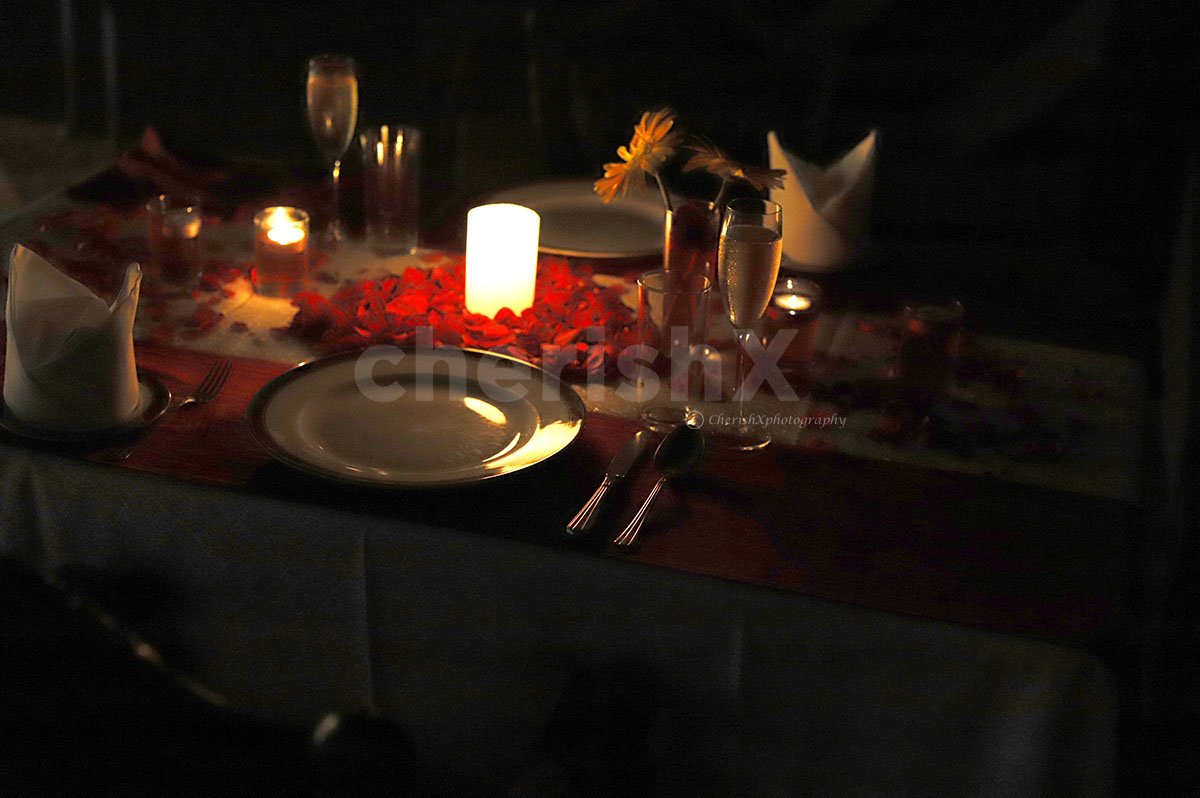 A Romantic Candle Light Dinner Arrangement with rose petals and candles.