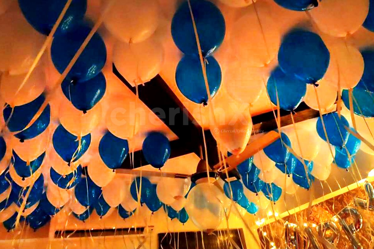 Blue and white balloons attached to the ceiling in preparation for a Balloon Surprise.