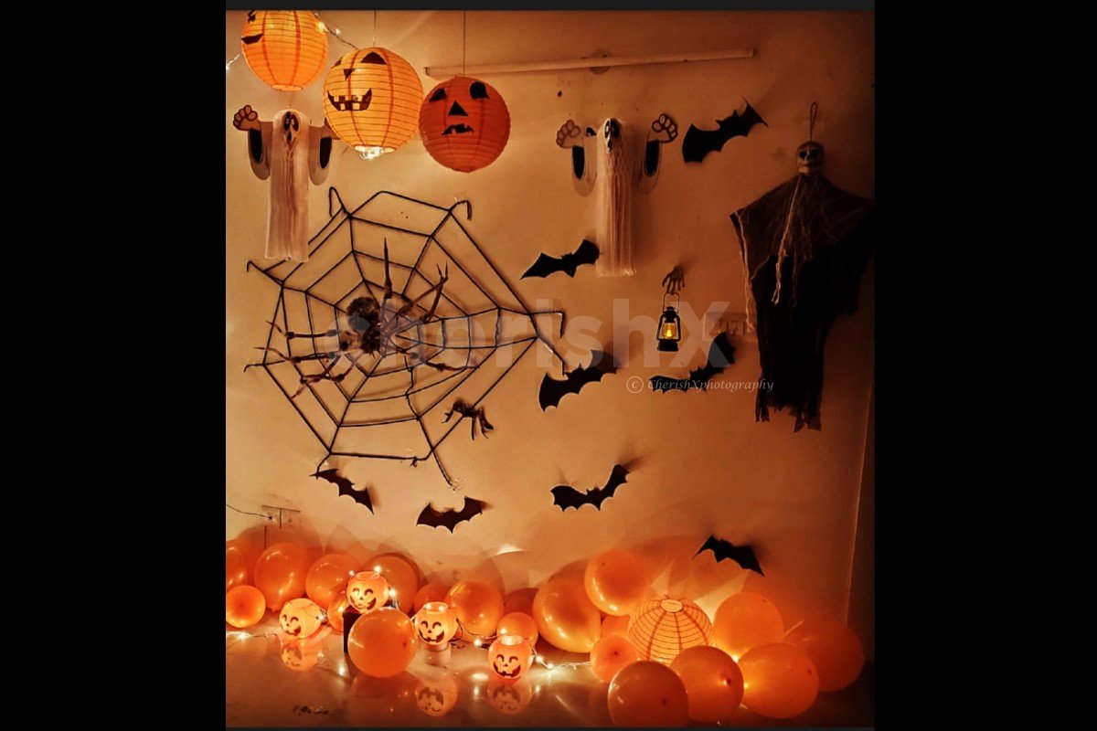 Halloween decoration at home on wall with spooky spider cut-outs, spider web, horror lanterns, and pumpkins