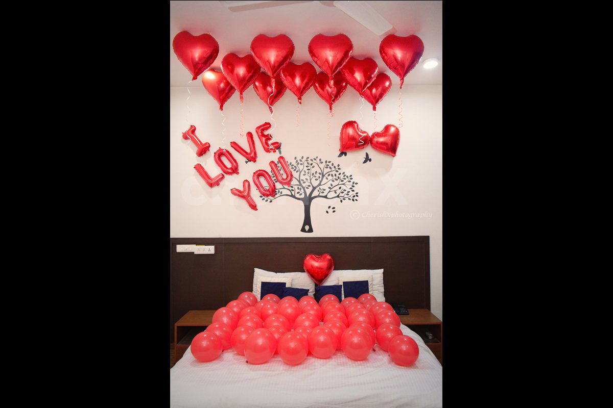 A room decorated with red balloons, foil balloons, and helium balloons for Valentine's day surprise 