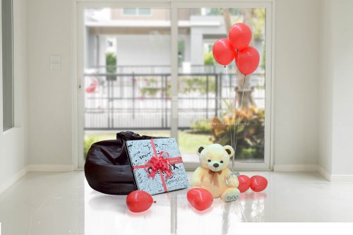 A Teddy Surplosion Box with a gift, teddy and balloons.