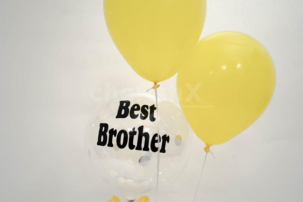 Two yellow balloons with a confetti balloon on which a message in vinyl is printed.
