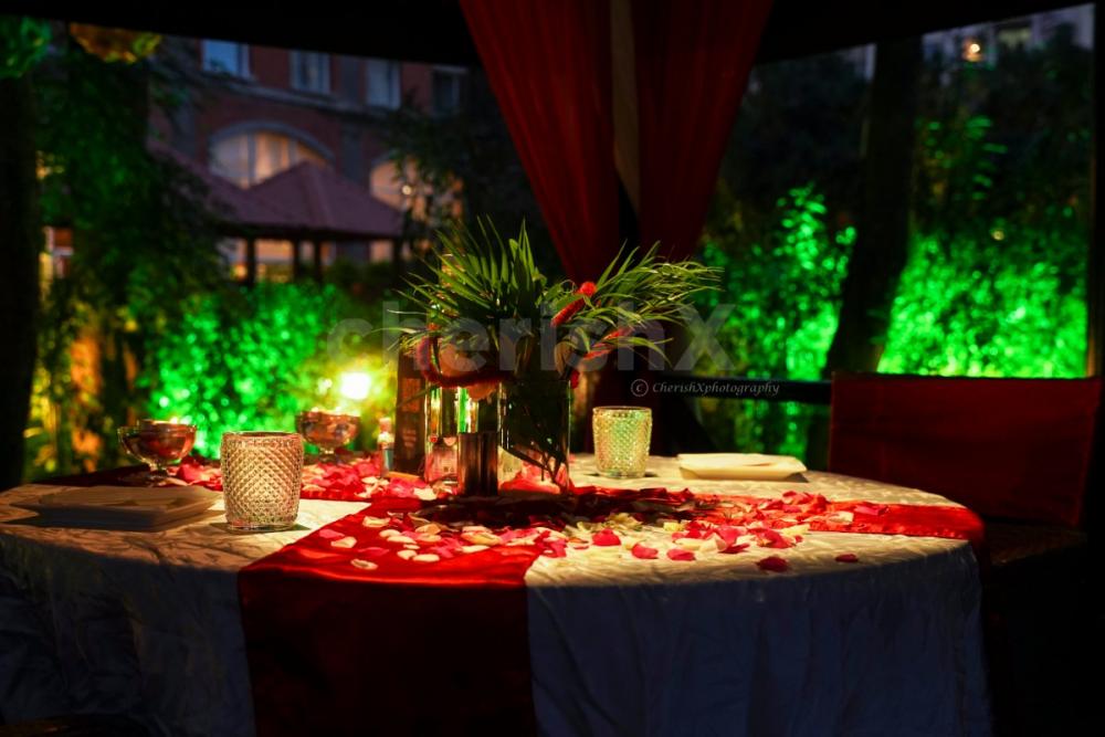 The Candlelight dinner table is decorated with flower petals and a small bouquet in the middle.