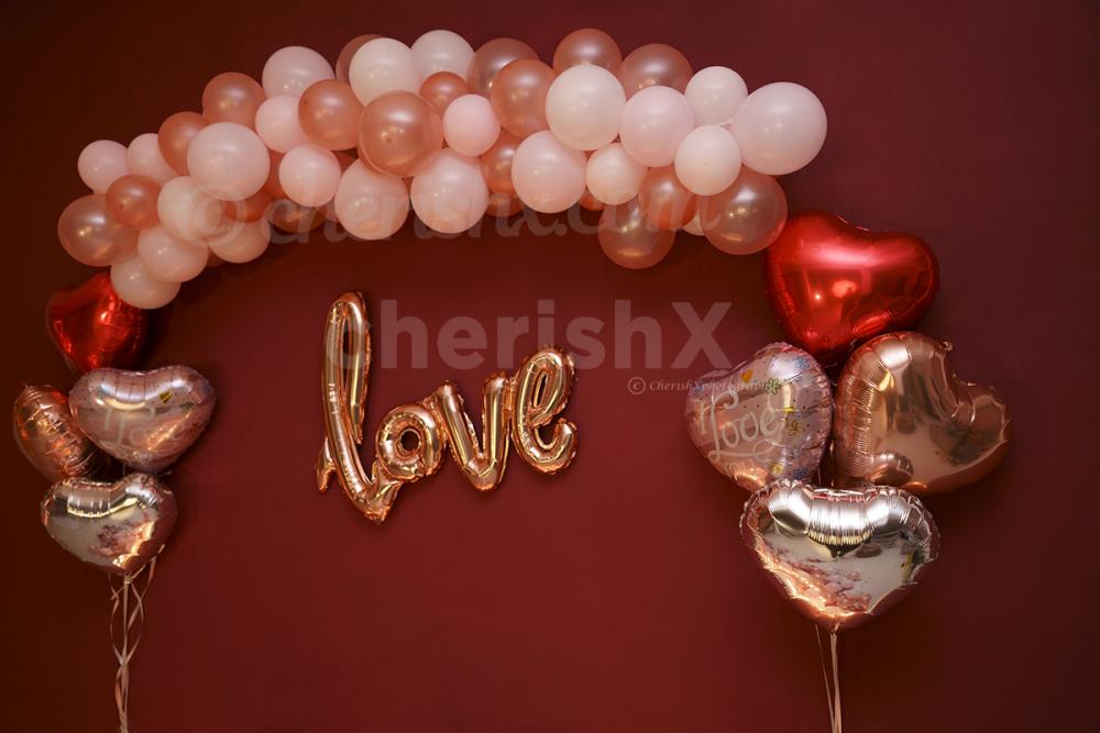 The wall decor with bunches of white and rose gold pastel balloons as well as some coloured Heart-shaped foil balloons.