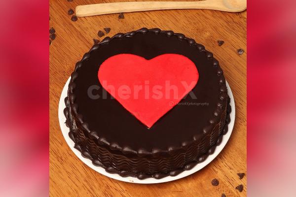 A chocolate flavoured cake with a heart on the top.
