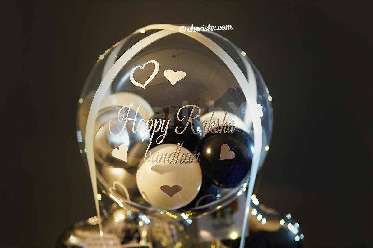 A Bubble balloon filled with silver, white, and black latex and chrome balloons highlights the whole bucket.