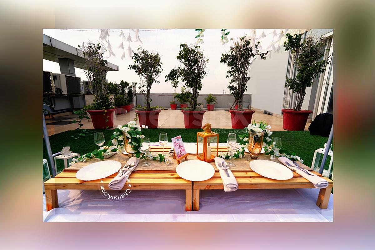 Low Dining Tables decorated with 2 Golden Vase filled with White Flower Bunches and 1 Golden Lamp placed on the table for the Boho Dining Experience.