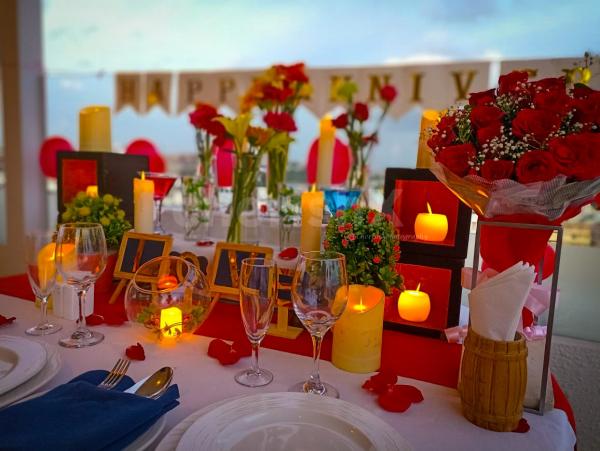 A Romantic Candle Light Dinner table decorated with Rose petals and candles.