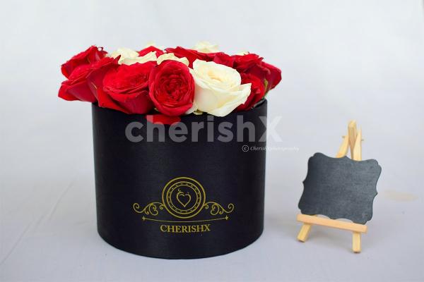 A bucket, full of red roses in which the letter is highlighted with white roses.