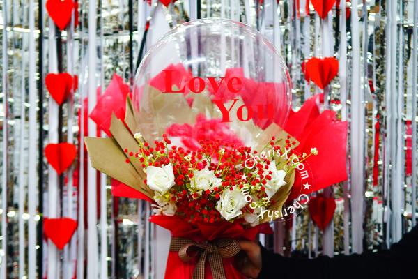 This unique bouquet combines classic red roses with cheerful balloons