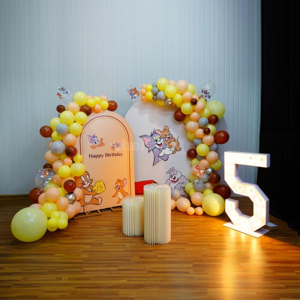 Our Tom & Jerry-themed backdrop is adorned with a captivating mix of peach pastels, yellow pastels, silver chrome, grey, and brown latex balloons.