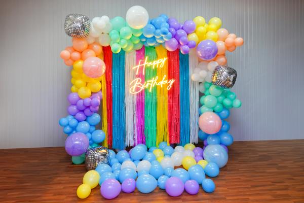 Transform Any Space with Our Neon-Lit Backdrop and Rainbow Arch Balloons.